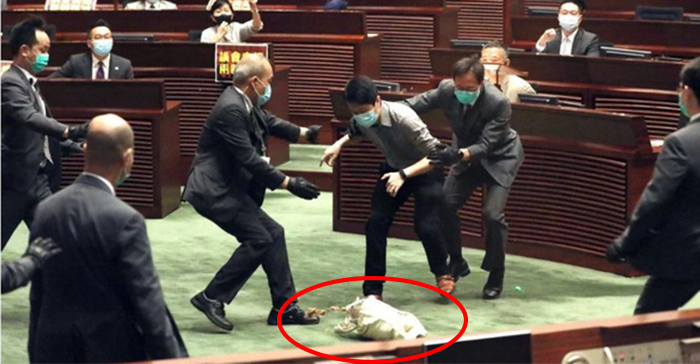 Nhân viên an ninh ngăn cản nghị sĩ Ted Hui Chi-fung khi ông cố ném túi đựng rau củ thối về hướng chủ tịch Hội đồng Lập pháp Hong Kong Andrew Leung ngày 28/5