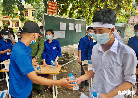Dũng nhận nước uống từ các bạn tình nguyện viên ở điểm thi Trường THPT Kỳ Sơn, huyện Kỳ Sơn, Nghệ An