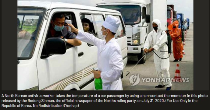 Một nhân của Bắc Triều Tiên đo nhiệt độ của hành khách