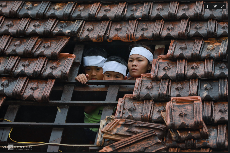 Chị Lê Thị Trang cùng 2 con, Đặng Ngọc Toàn (9 tuổi) và Đặng Ngọc Diện (8 tuổi) ló đầu qua mái ngói khi thấy lực lượng cứu trợ.