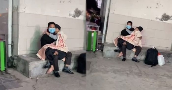 Chàng trai bế cụ bà vào lòng giữa trời đông, trong hành lang một bệnh viện.