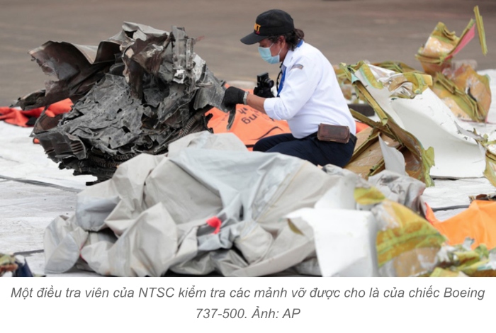 Một điều tra viên của NTSC kiểm tra các mảnh vỡ được cho là của chiếc Boeing 737-500. Ảnh: AP

