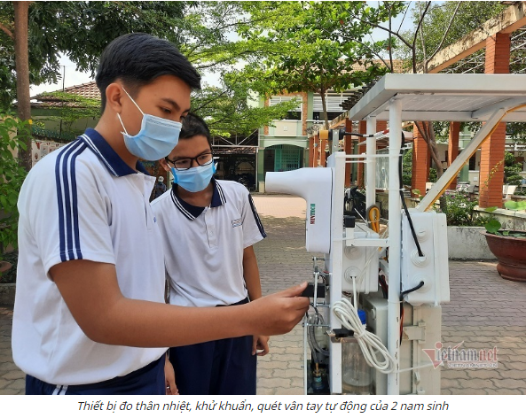 Ảnh chụp màn hình báo VietNamNet hai nam sinh bên chiếc máy đo thân nhiệt của mình