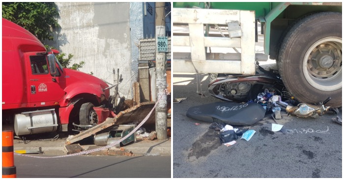 Phần tường rào của một công ty bên đường bị xe container tông sập, cùng Chiếc xe máy bị cán nát.