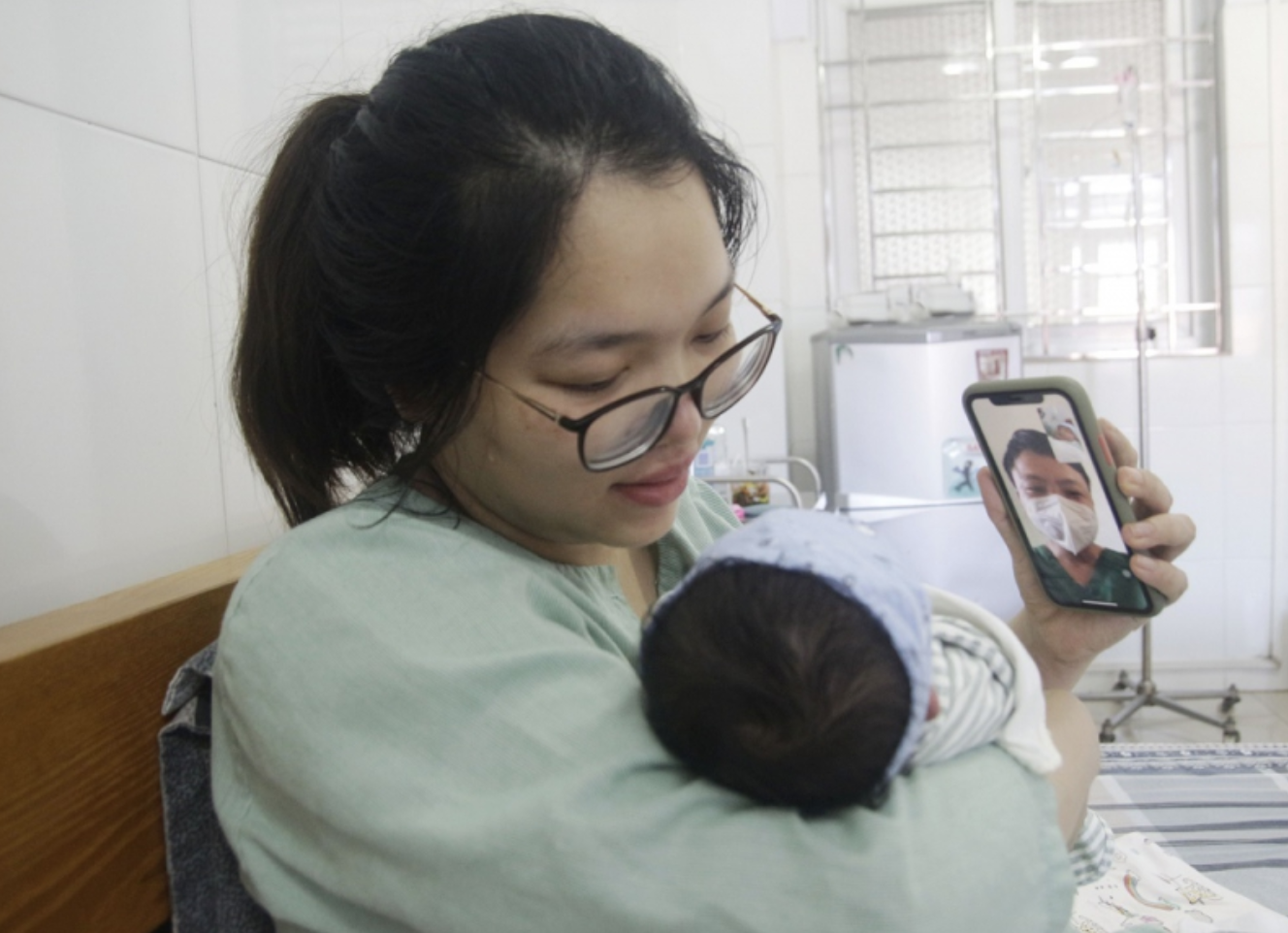 Bác sĩ Nghĩa nhìn con gái mới sinh qua điện thoại (ảnh chụp màn hình trên trang Benhvienbaichay).