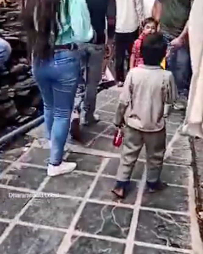 Cậu bé đi chân đất nhắc nhở từng du khách đeo khẩu trang trên phố (ảnh căt từ clip).