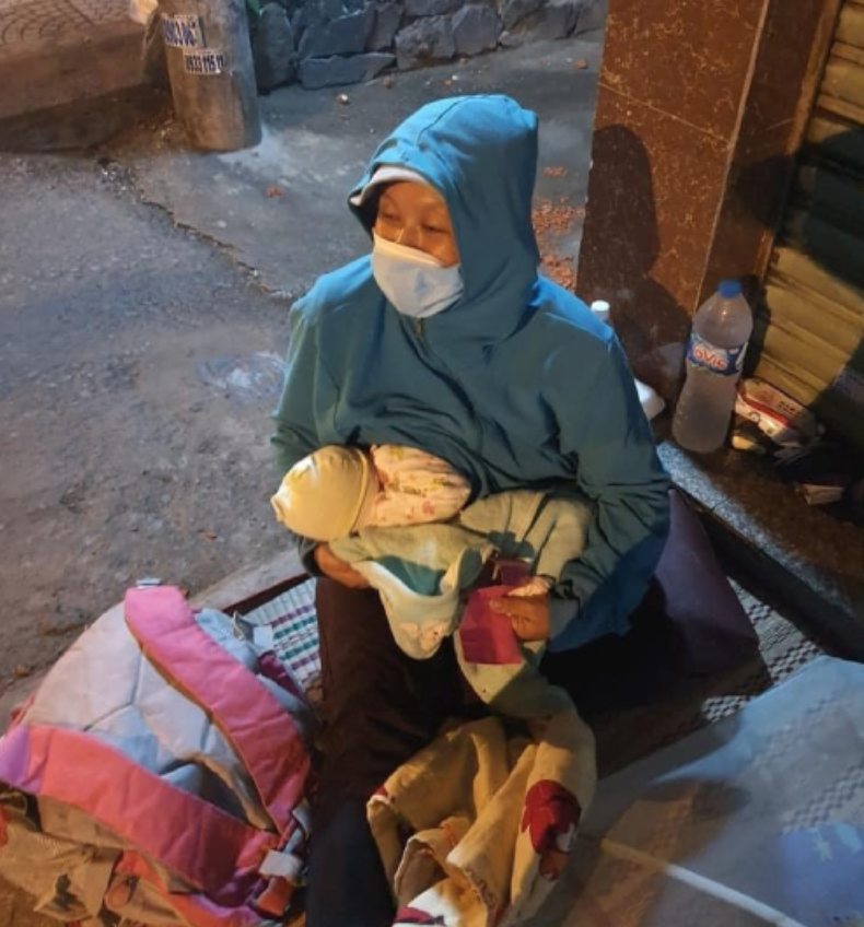 Chị Bé Tư ôm con mới sinh được 2 tháng ngồi ngoài đường (ảnh chụp màn hình trên Ngoisao.net).