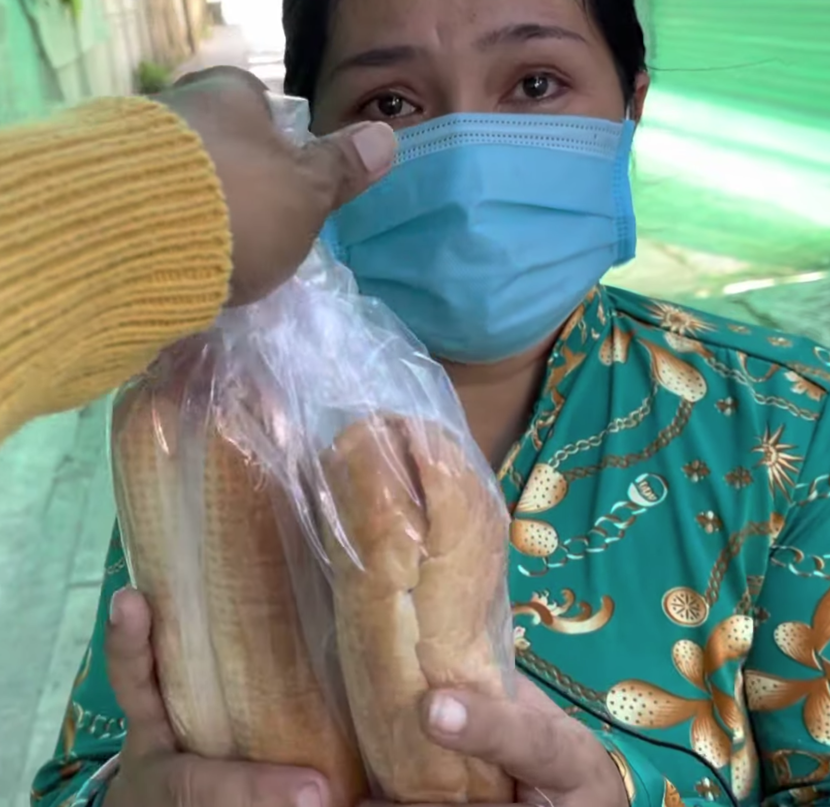Người phụ nữ nhận 2 chiếc bánh mì không mà nước mắt đã trực trào (ảnh chụp màn hình video).