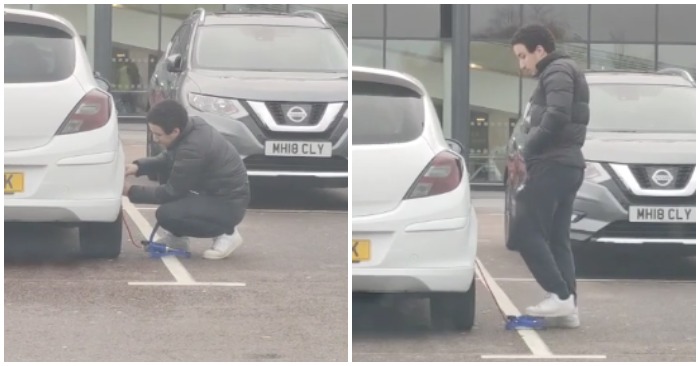 Nam thanh niên đang bơm lốp xe ô tô của mình bằng một bơm mini bằng chân (ảnh cắt từ clip).