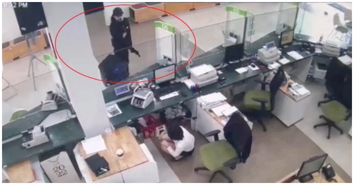 Tên cướp dùng súng uy hiếp nhân viên ngân hàng để cướp tiền (ảnh chụp màn hình trên báo Zing).
