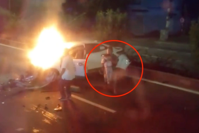 Bé gái được đưa ra khỏi chiếc ô tô bốc cháy (ảnh chụp từ clip).